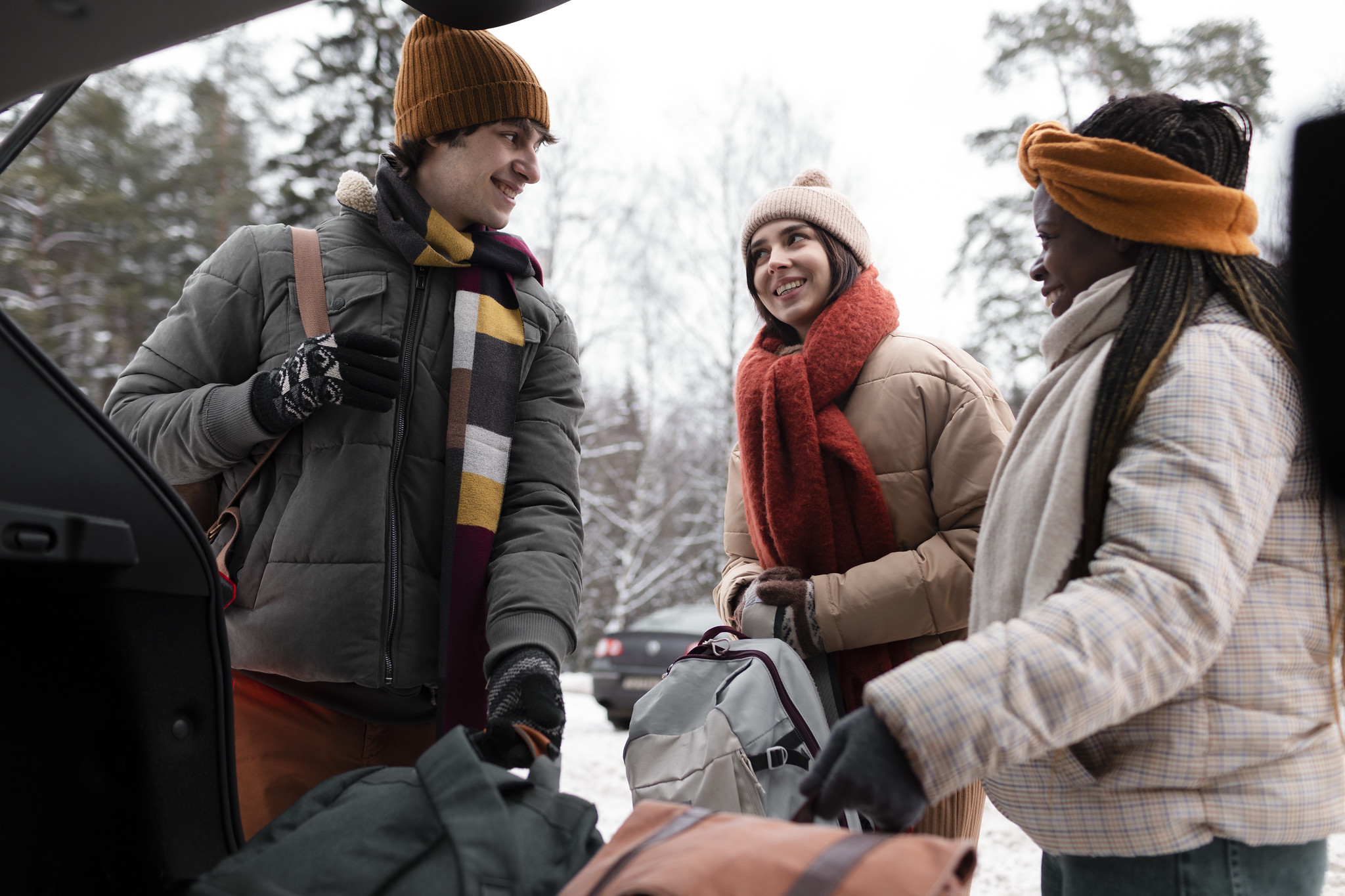 Travellers loading bags into a car boot before setting off on a winter road trip